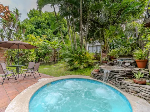 Piscina de hidromasaje exterior con cascada y jardín tropical