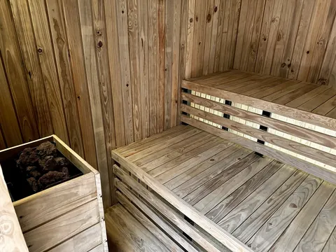 Sauna seco de Lúmina Spa con bancas de madera y piedras volcánicas